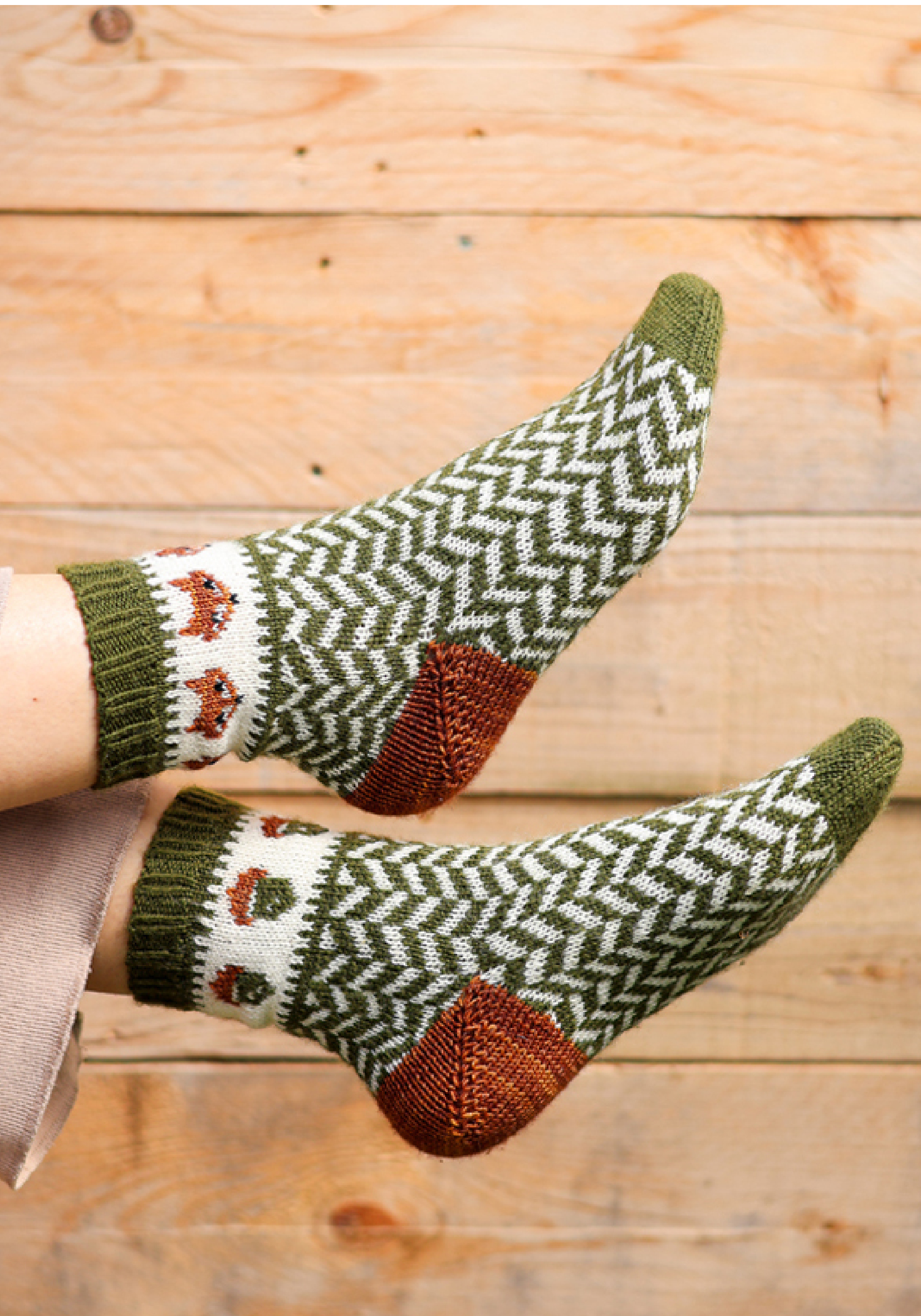 Chaussettes tricotées vertes et blanches à motifs géométriques et automnaux, portées sur fond bois, idéales pour tricot DIY, chaussettes handmade, accessoires hiver et style cosy scandinave